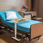 White electric adjustable overbed table next to upholstered bed in modern bedroom