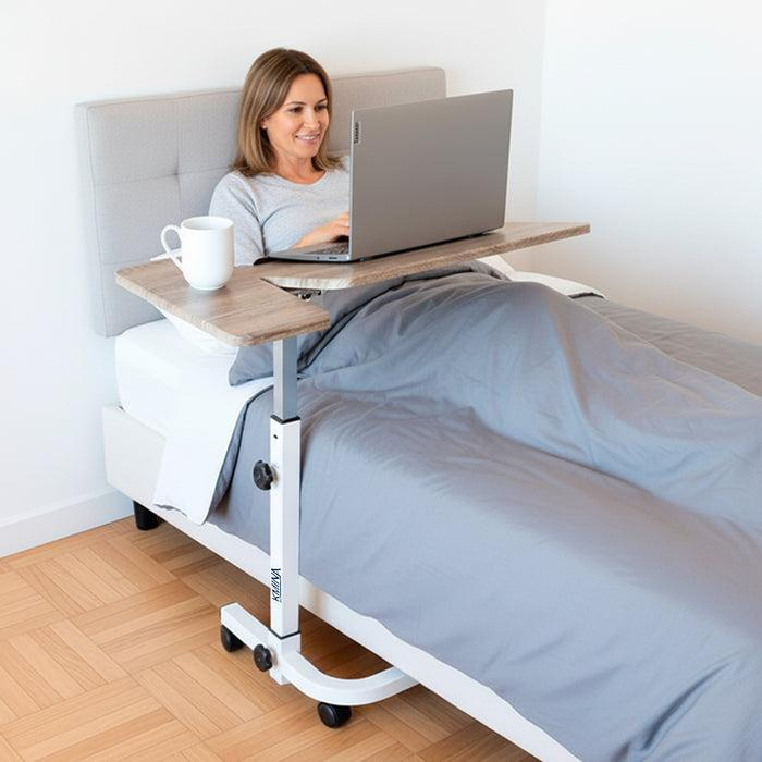 White adjustable overbed table with tilting top and lockable castors in bright bedroom