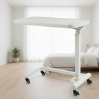 Overbed table with food tray positioned over hospital bed with blue mattress