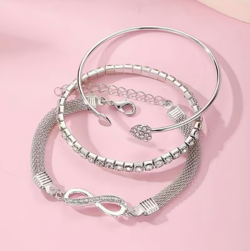 Argenté Trio Bracelet Set – Silver-tone infinity, crystal tennis & heart charm bangles on pink background