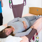 Nurse assisting elderly patient to stand using transfer aid and wheelchair