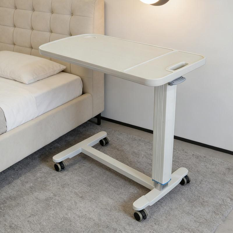White overbed table with laptop and snacks positioned over hospital bed
