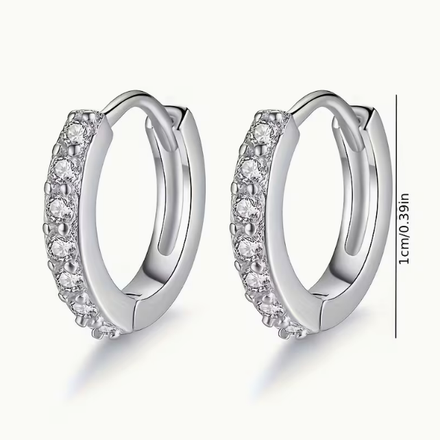 Lumière Pavé Huggie Hoop Earrings – silver huggie hoops on wooden surface with white flower