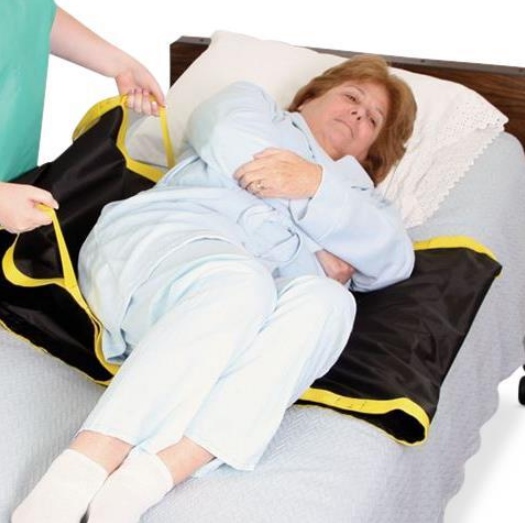 Patient turning aid with yellow handles used to reposition elderly woman in bed
